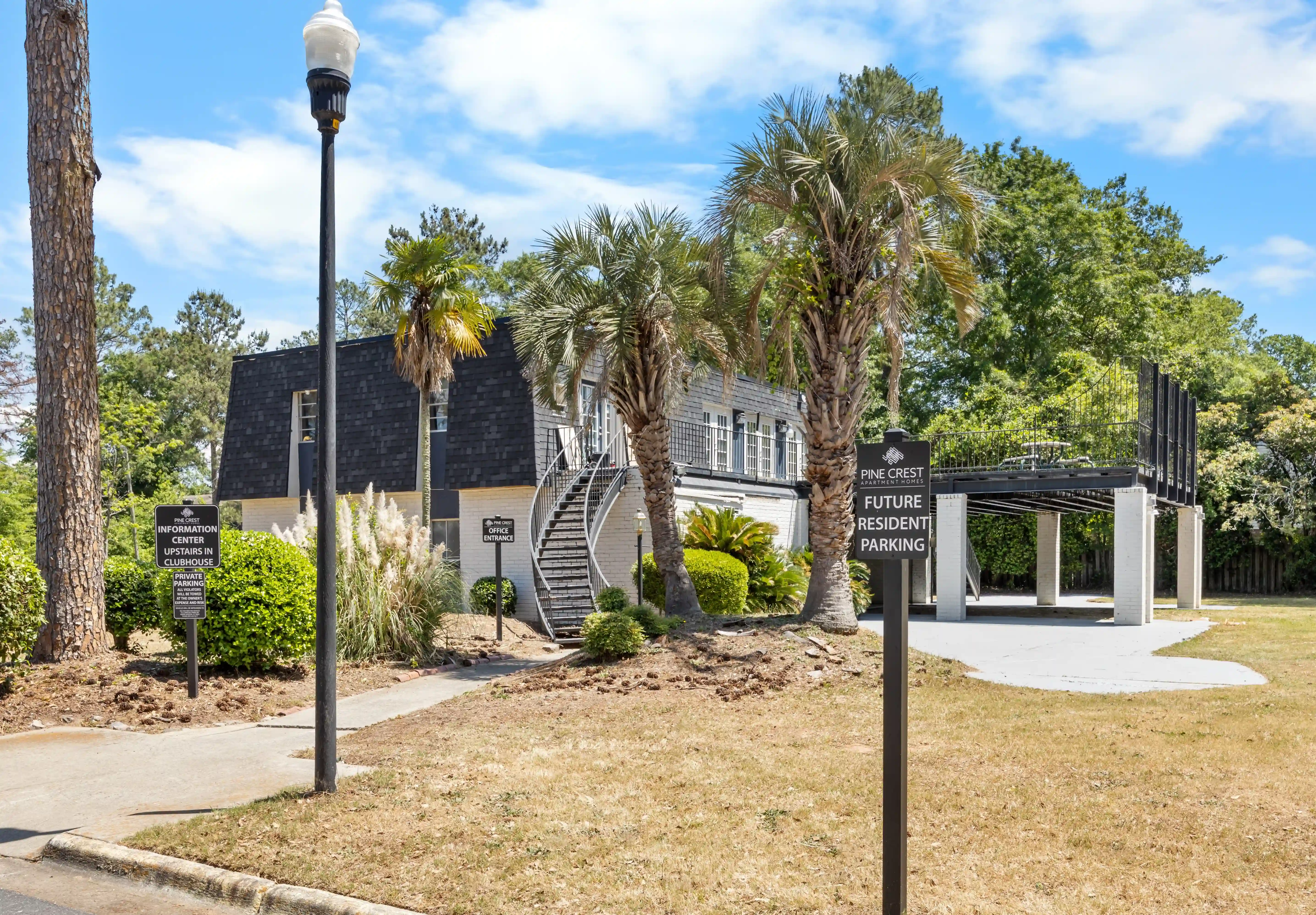 Apartment community leasing office building with palm trees, resident parking area, and landscaped exterior.