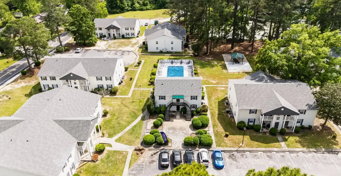 Aerial view of Arbor Landing apartment community featuring multiple buildings, landscaped grounds, a swimming pool, picnic pavilion, walkways, and parking.